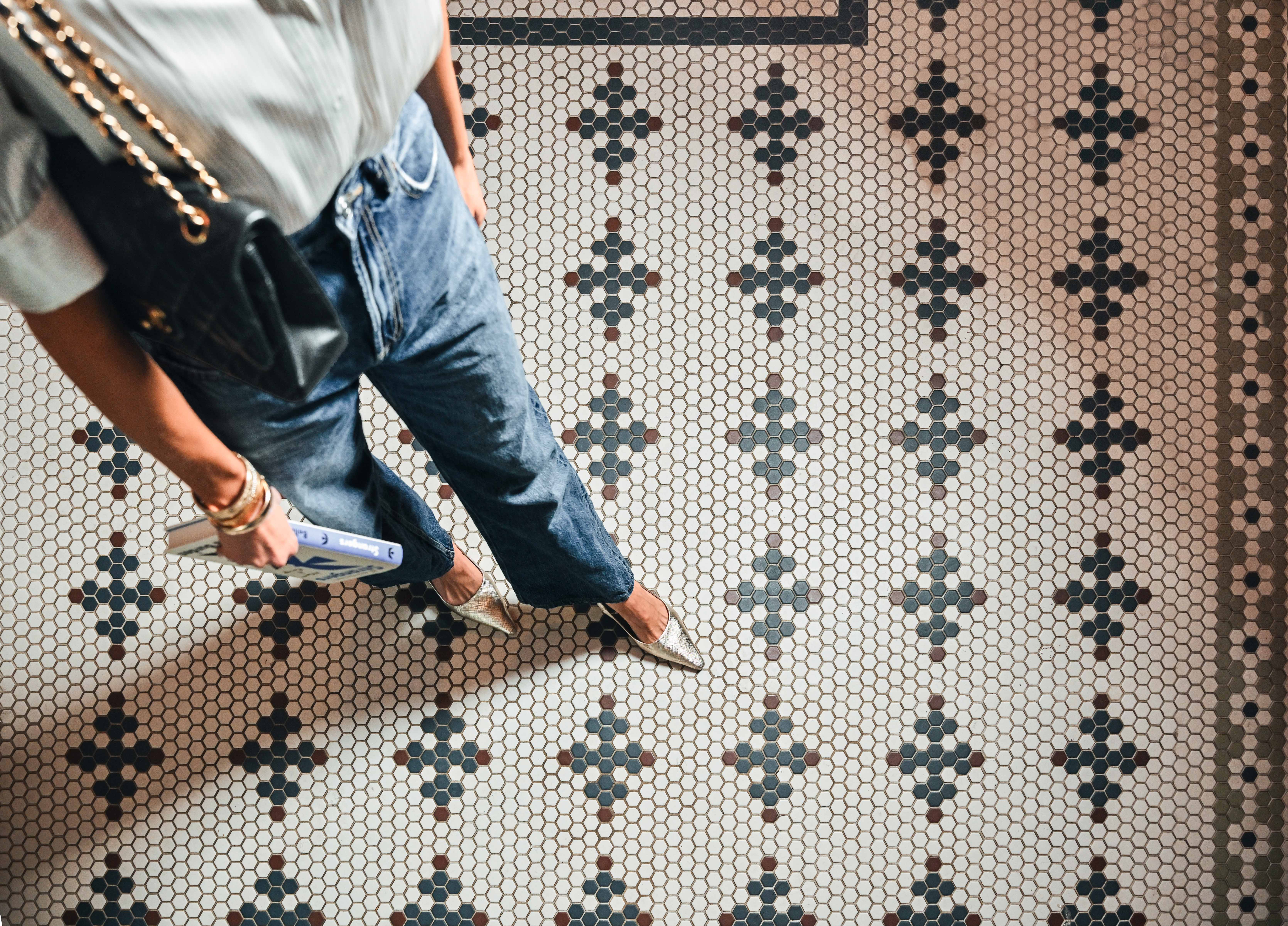 Woman in jeans walking confidently across a mosaic tile floor