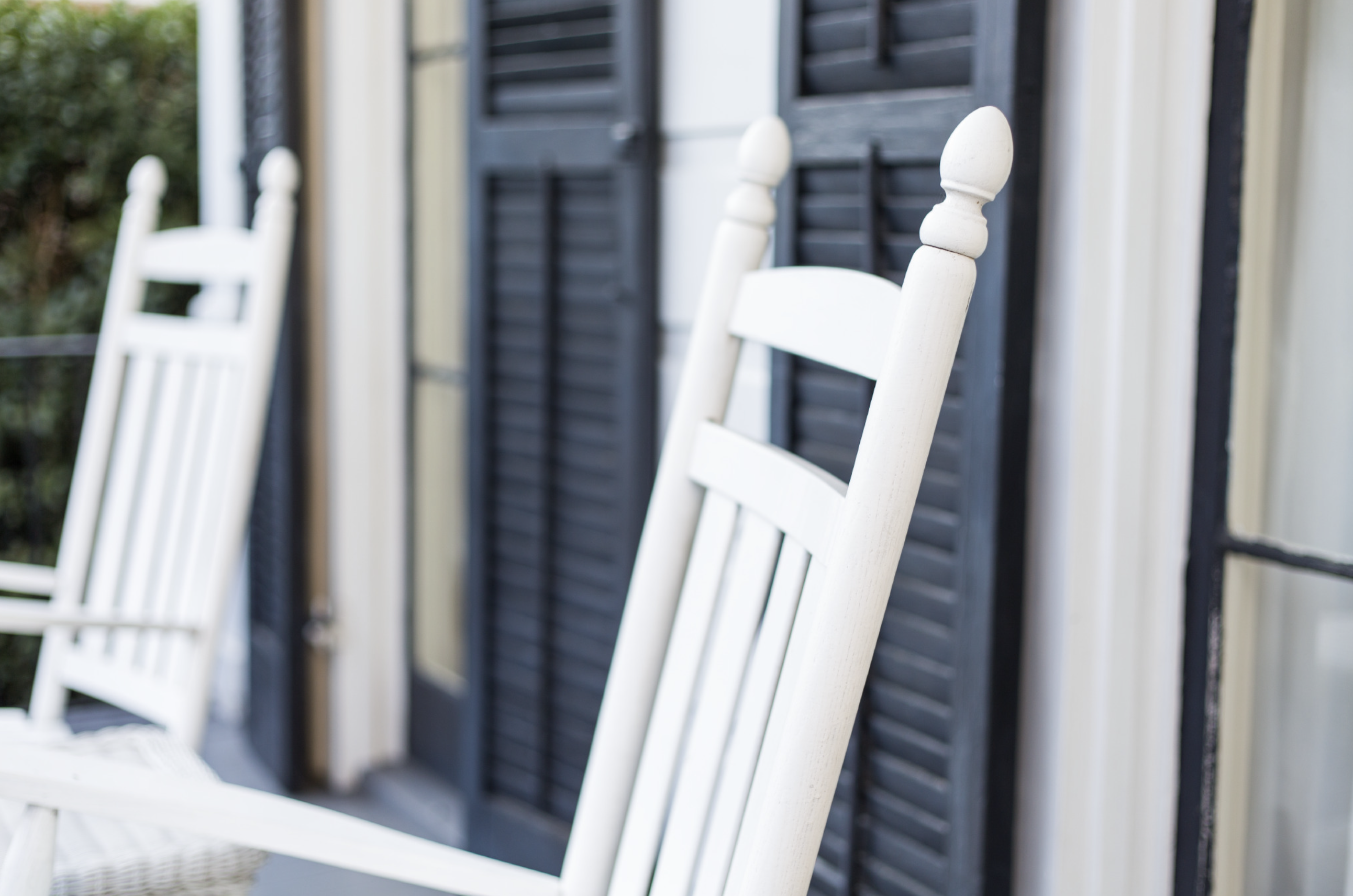 Quiet porch with white rocking chairs, evoking a peaceful moment of reflection